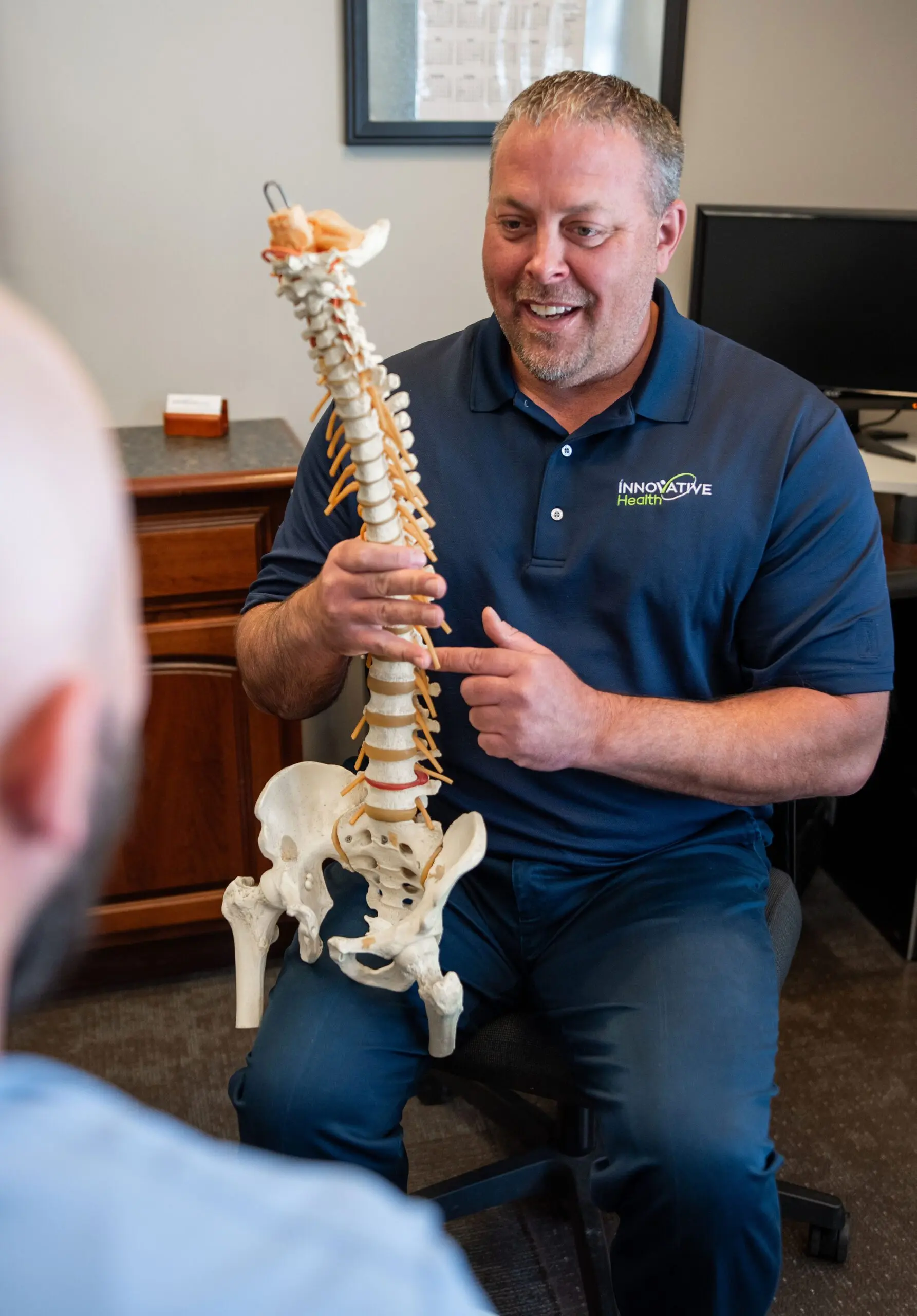 Chiropractor using a spine model to explain treatment to a patient