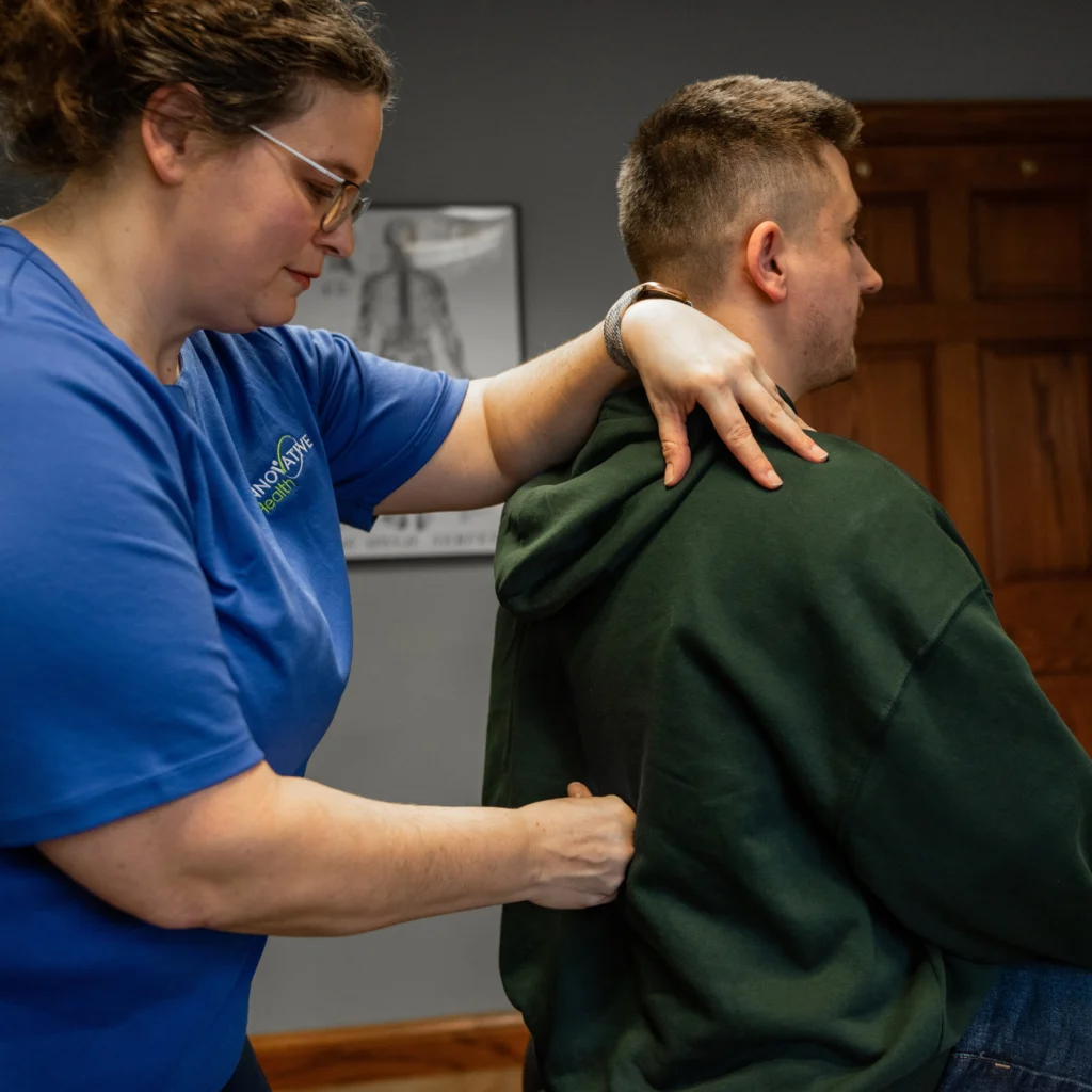 Chiropractor performing a back and shoulder assessment on a male patient