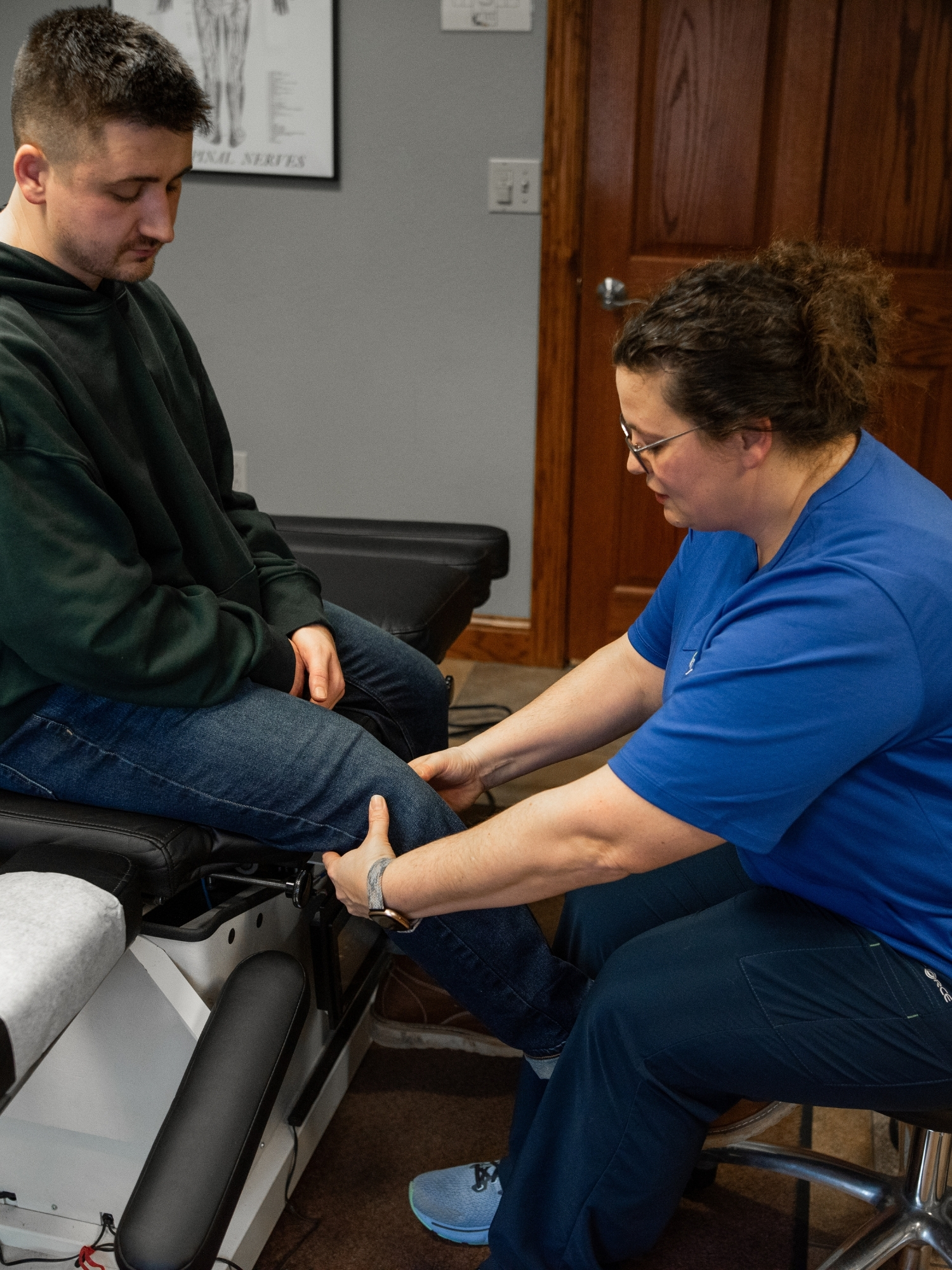 Chiropractor examining a male patient’s knee during a treatment session